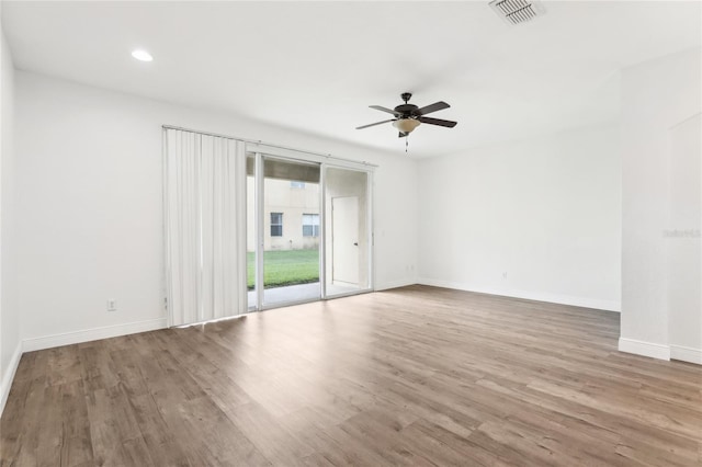 spare room featuring baseboards, visible vents, ceiling fan, and wood finished floors