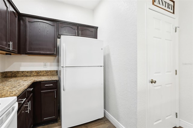 kitchen with baseboards, range, dark wood-style floors, freestanding refrigerator, and dark brown cabinets