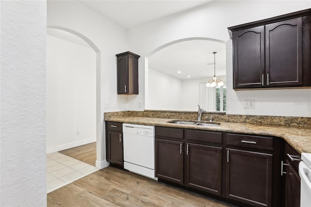 kitchen featuring light wood-style floors, white dishwasher, a sink, and dark brown cabinets