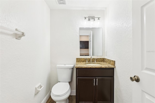 bathroom with visible vents, baseboards, toilet, wood finished floors, and vanity