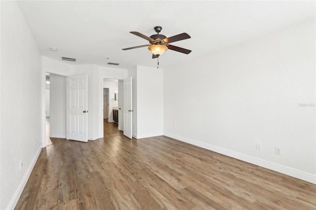 spare room with baseboards, visible vents, and wood finished floors