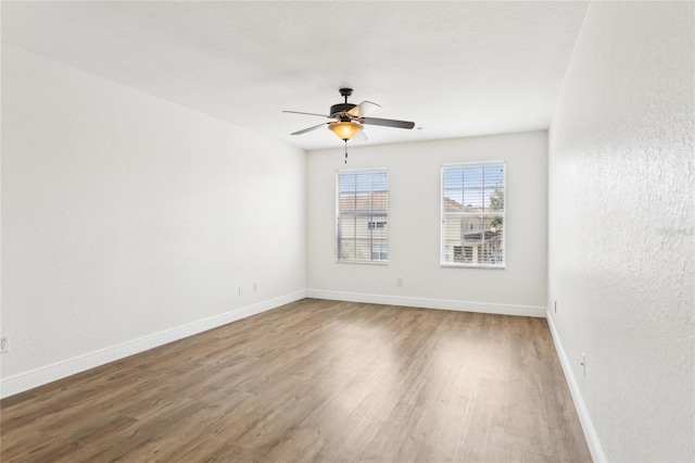 empty room with a ceiling fan, baseboards, and wood finished floors