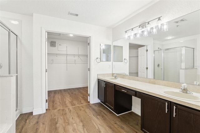 full bath with wood finished floors, a stall shower, a sink, and a walk in closet