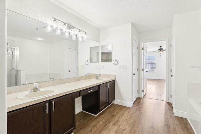 full bath with a garden tub, wood finished floors, a sink, baseboards, and double vanity