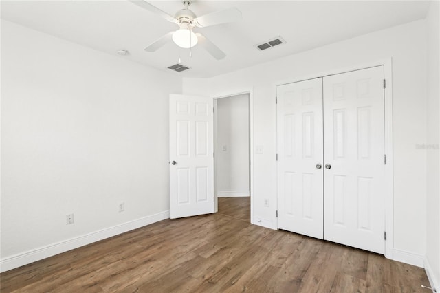 unfurnished bedroom featuring a closet, visible vents, baseboards, and wood finished floors