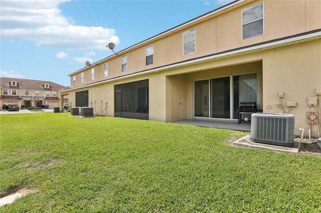 back of house with stucco siding, central AC, and a yard