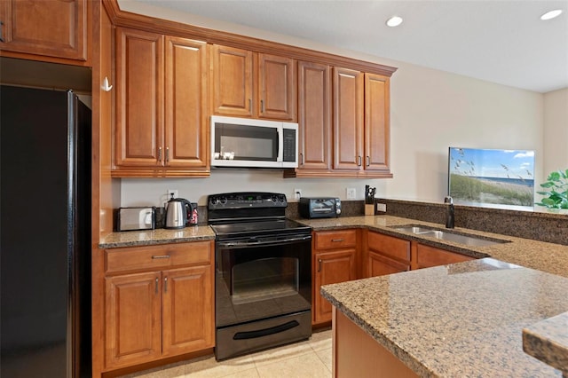 kitchen with black appliances, recessed lighting, a sink, and light stone countertops