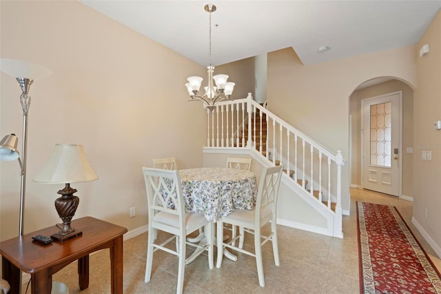 dining room with arched walkways, light tile patterned floors, stairway, a chandelier, and baseboards