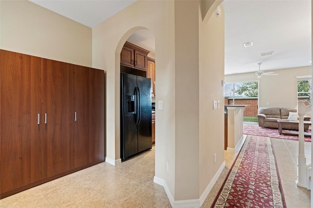 corridor with arched walkways, visible vents, and baseboards