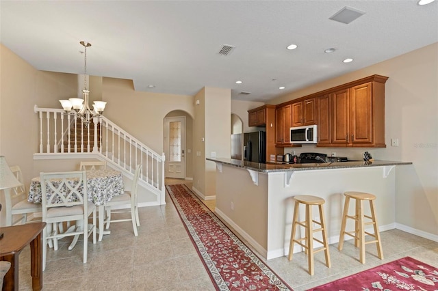 kitchen with visible vents, arched walkways, brown cabinetry, white microwave, and black refrigerator with ice dispenser