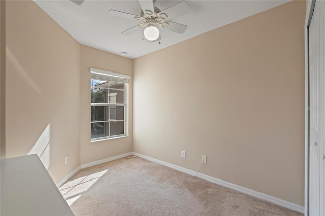 empty room featuring light carpet, baseboards, and a ceiling fan