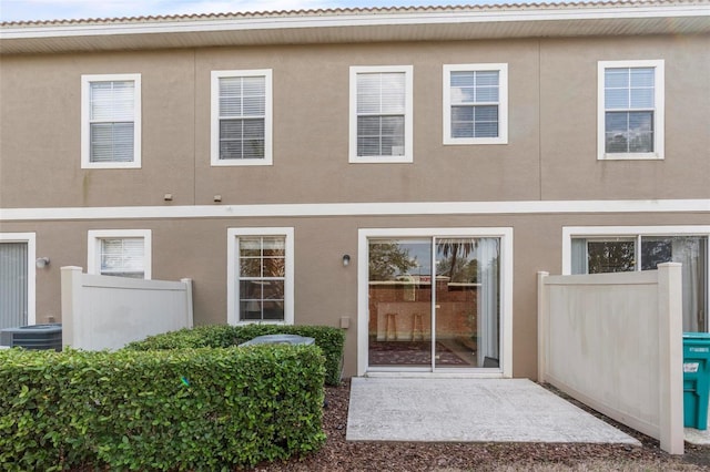 exterior space with central AC unit, fence, and stucco siding