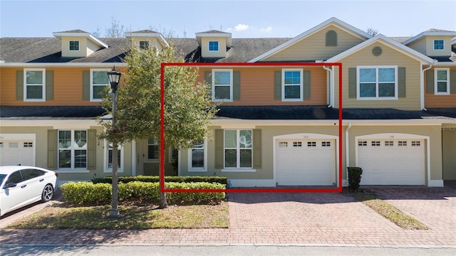 multi unit property with driveway, an attached garage, and stucco siding