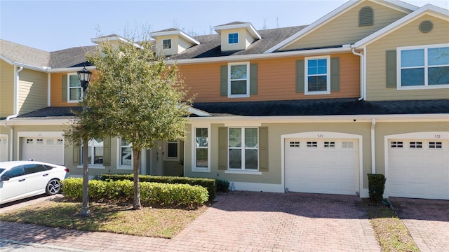 multi unit property with driveway, roof with shingles, a garage, and stucco siding