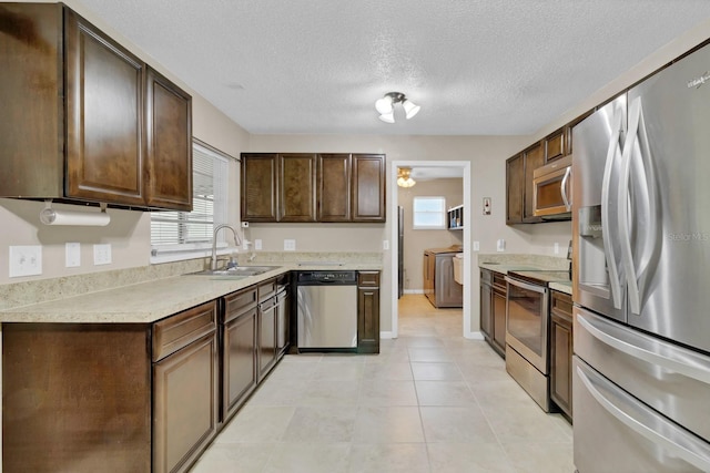 kitchen featuring dark brown cabinets, light countertops, independent washer and dryer, stainless steel appliances, and a sink