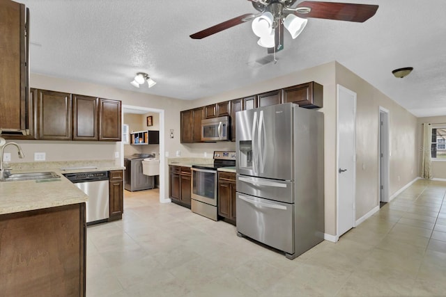 kitchen featuring a sink, light countertops, dark brown cabinets, appliances with stainless steel finishes, and a textured ceiling