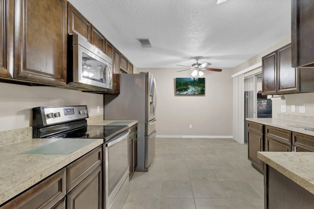 kitchen featuring visible vents, dark brown cabinets, light countertops, stainless steel appliances, and a ceiling fan