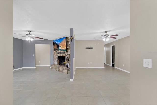 unfurnished living room featuring a textured ceiling, a fireplace, a ceiling fan, and baseboards