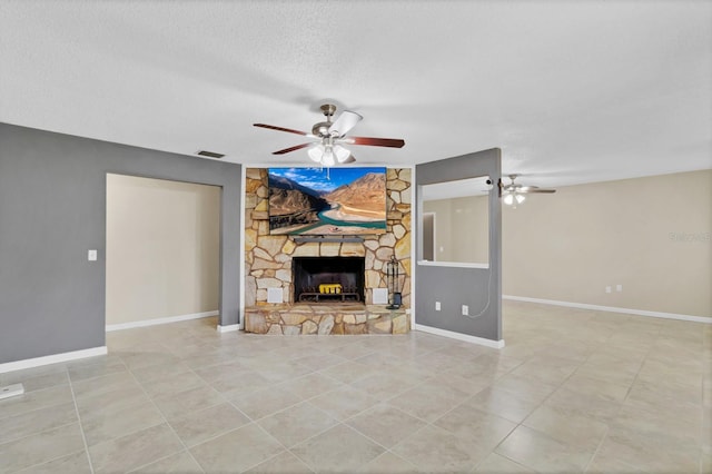 unfurnished living room featuring visible vents, a textured ceiling, a stone fireplace, baseboards, and ceiling fan