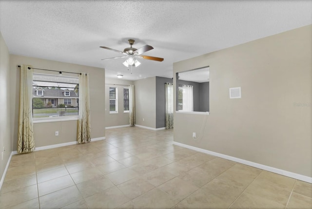 empty room featuring baseboards, a textured ceiling, ceiling fan, and light tile patterned flooring