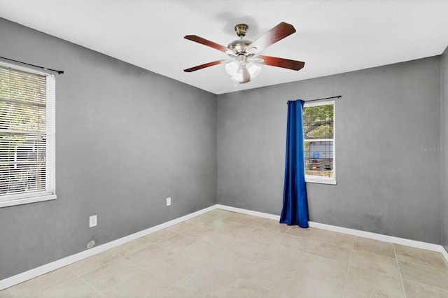 empty room featuring a ceiling fan and baseboards