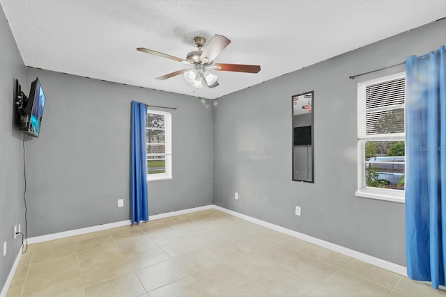 spare room featuring a wealth of natural light, baseboards, and a ceiling fan