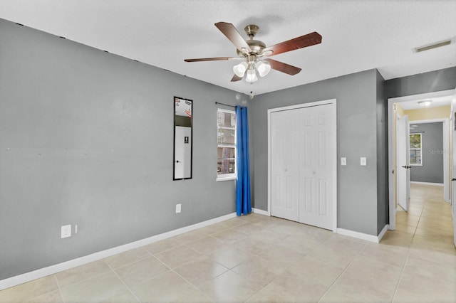 unfurnished bedroom with visible vents, baseboards, ceiling fan, light tile patterned floors, and a closet