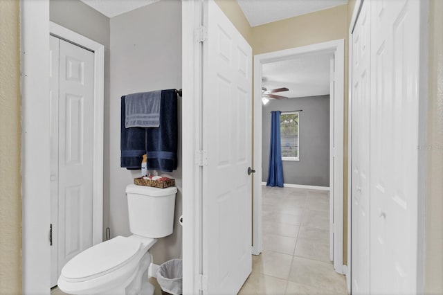 bathroom with a closet, baseboards, toilet, and tile patterned flooring