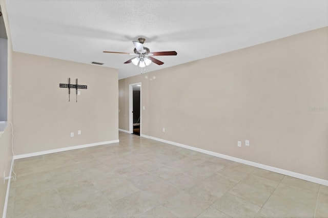 empty room with visible vents, ceiling fan, a textured ceiling, and baseboards