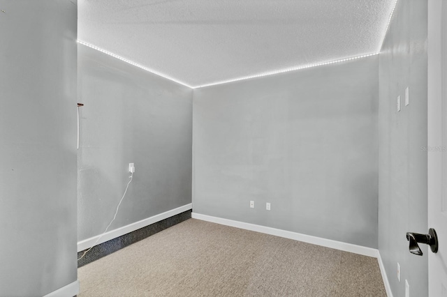 carpeted empty room featuring a textured ceiling and baseboards