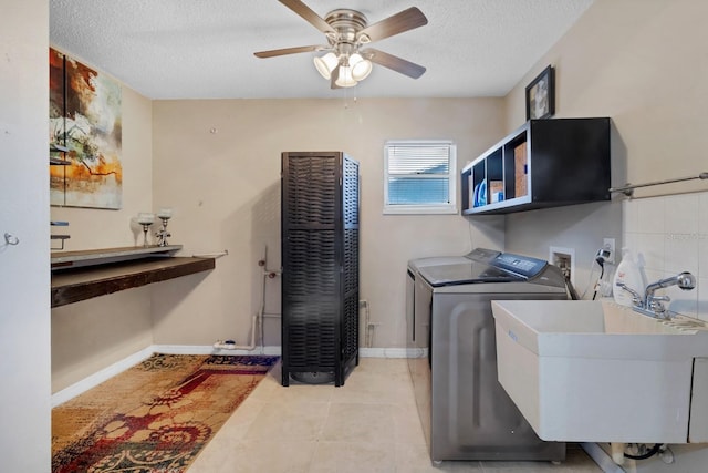 washroom with laundry area, light tile patterned flooring, a sink, a textured ceiling, and washing machine and dryer