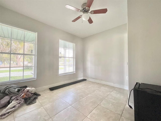 unfurnished room featuring light tile patterned floors, a ceiling fan, and baseboards