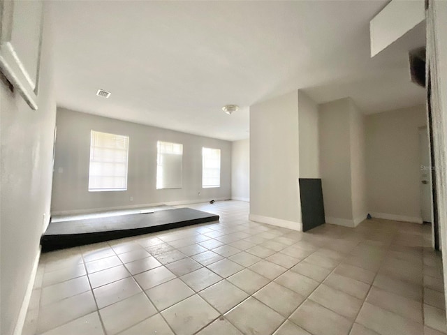 empty room with light tile patterned floors, baseboards, and visible vents