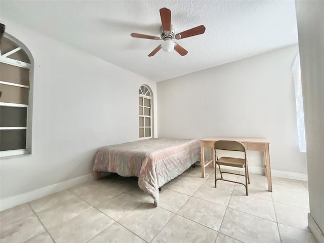 bedroom with light tile patterned floors, a textured ceiling, baseboards, and a ceiling fan