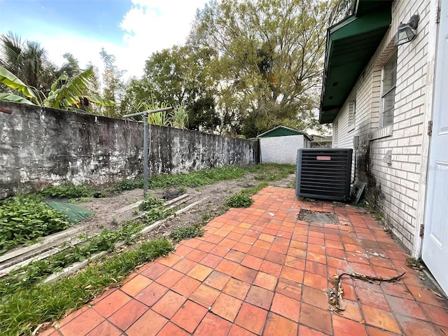 view of patio featuring a fenced backyard, cooling unit, and an outbuilding