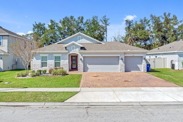 view of front of property featuring stone siding, a front yard, decorative driveway, and stucco siding