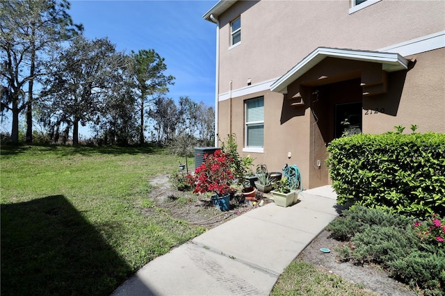 property entrance featuring a yard, central air condition unit, and stucco siding