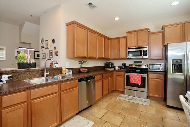 kitchen with a toaster, dark countertops, visible vents, appliances with stainless steel finishes, and a sink