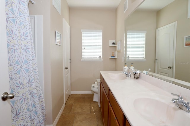 bathroom with baseboards, a sink, toilet, and double vanity