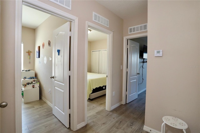 corridor with visible vents and light wood-style floors