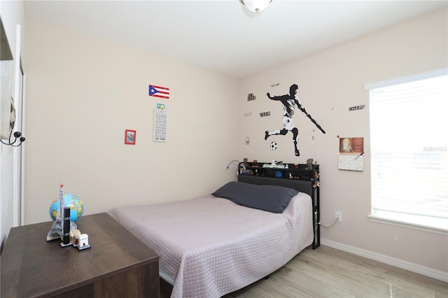 bedroom with baseboards, multiple windows, and light wood-style floors