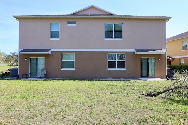 back of house with stucco siding, central AC, and a yard