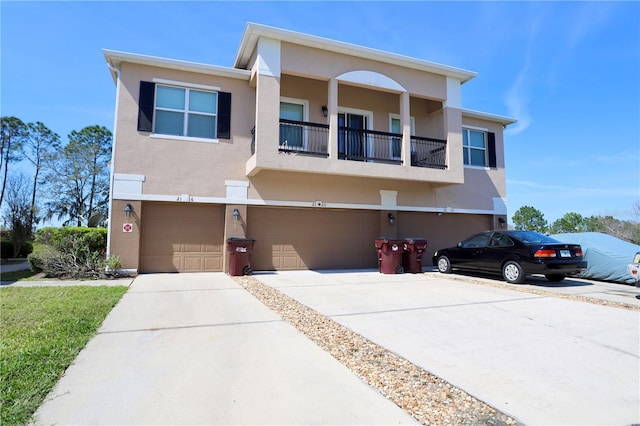 view of front facade with driveway, a balcony, an attached garage, and stucco siding