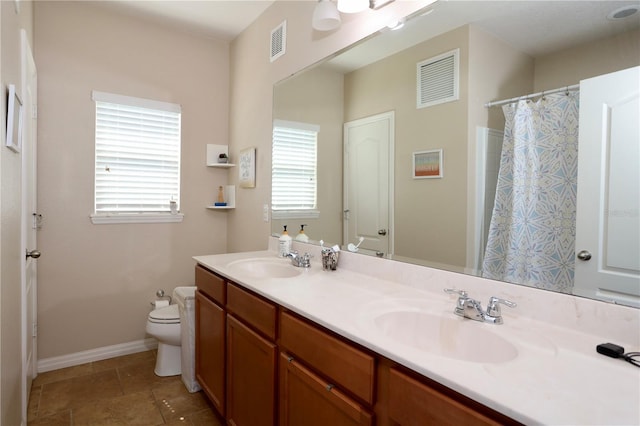 bathroom with toilet, a sink, and visible vents