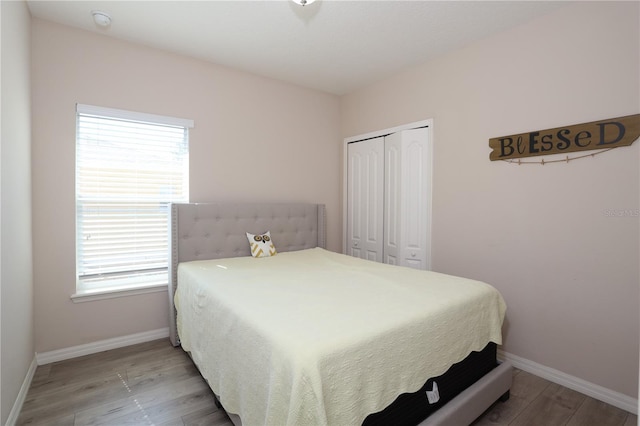 bedroom with light wood-type flooring, a closet, and baseboards