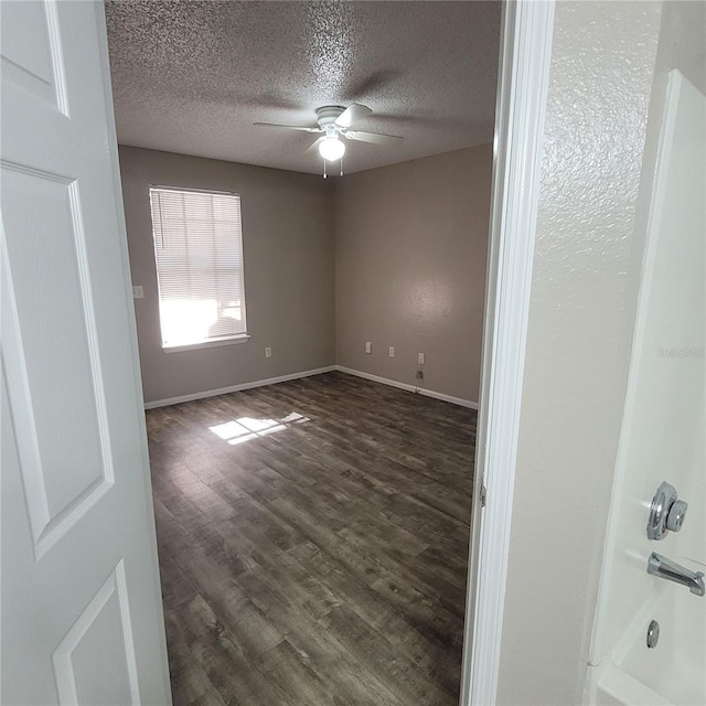 unfurnished room featuring baseboards, a textured ceiling, a ceiling fan, and dark wood-style flooring