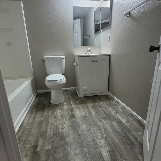 bathroom with a textured wall, toilet, and wood finished floors