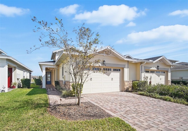 view of front of home featuring stone siding, stucco siding, an attached garage, decorative driveway, and a front yard