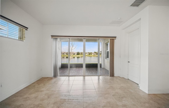 spare room featuring visible vents, a water view, baseboards, and light tile patterned flooring