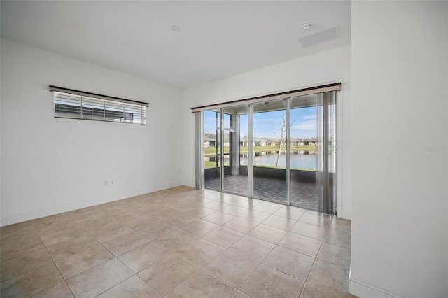 spare room with visible vents, a water view, baseboards, and light tile patterned floors